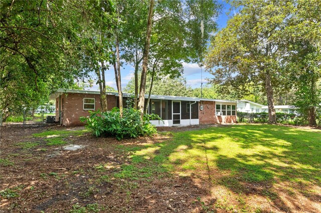 rear view of house with a sunroom and a yard