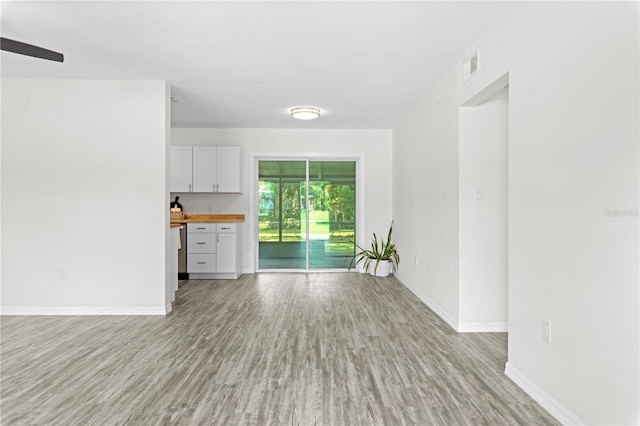 unfurnished living room with light wood-style floors, visible vents, and baseboards