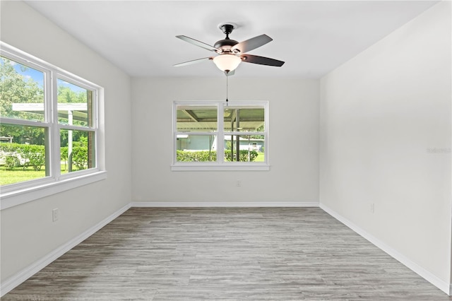 spare room with light wood-style floors, a healthy amount of sunlight, baseboards, and a ceiling fan