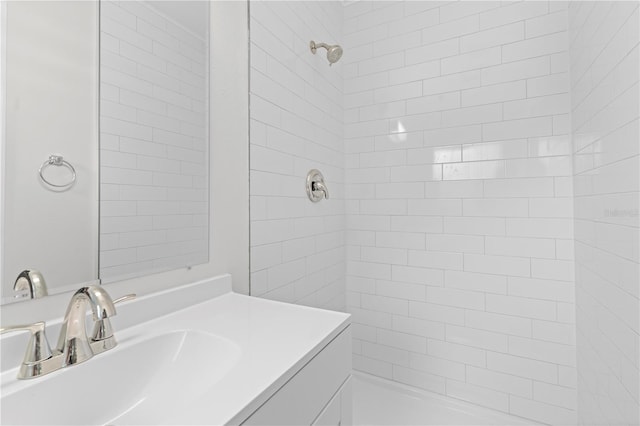 bathroom featuring tiled shower and vanity