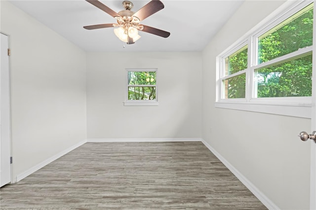 spare room featuring ceiling fan, light wood-type flooring, and baseboards