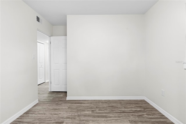 spare room featuring wood finished floors, visible vents, and baseboards