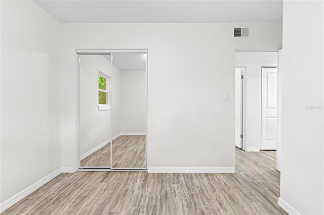 unfurnished bedroom with a closet and light hardwood / wood-style floors