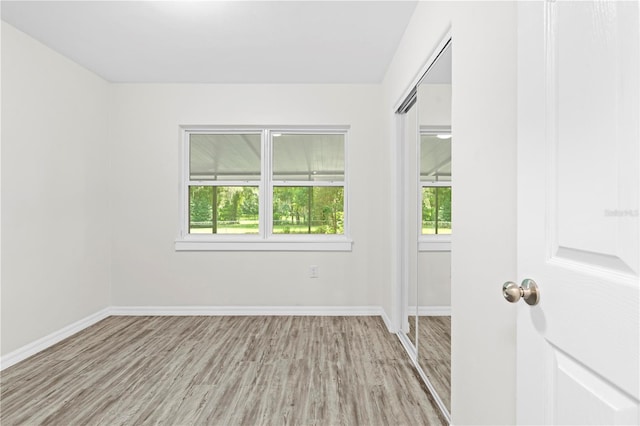 spare room featuring baseboards, plenty of natural light, and light wood finished floors