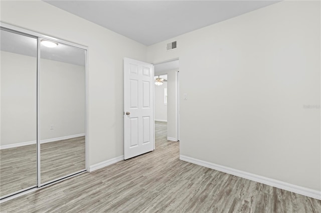 unfurnished bedroom featuring light wood-style floors, a closet, visible vents, and baseboards