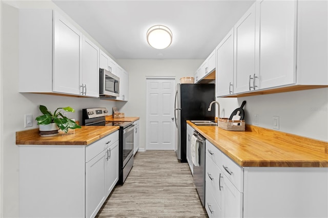 kitchen with stainless steel appliances, wood counters, white cabinetry, and light wood-style floors