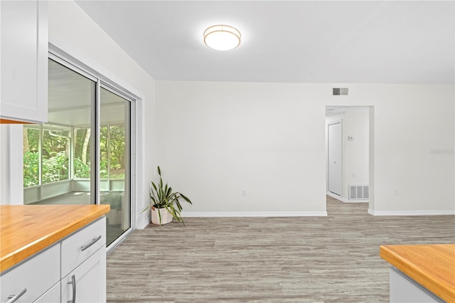 empty room featuring light wood-style flooring, visible vents, and baseboards