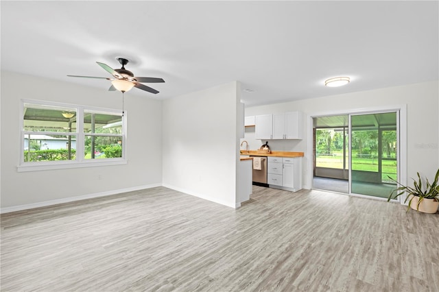 unfurnished living room with sink, ceiling fan, and light hardwood / wood-style floors