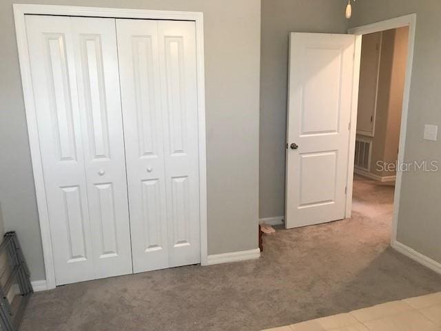 unfurnished bedroom featuring a closet and light colored carpet