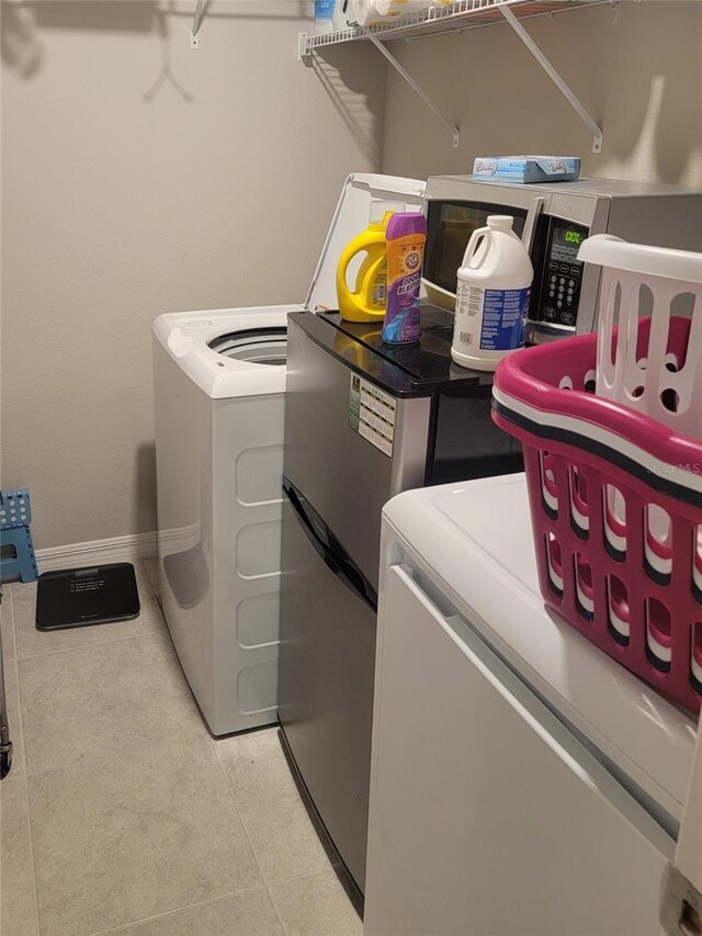 14443 Touch Gold Ln, Sun City Center, FL 33573 - laundry area featuring light tile patterned floors, washing machine and clothes dryer, and baseboards