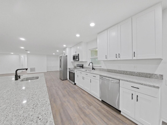 kitchen with white cabinets, light wood-type flooring, stainless steel appliances, and sink