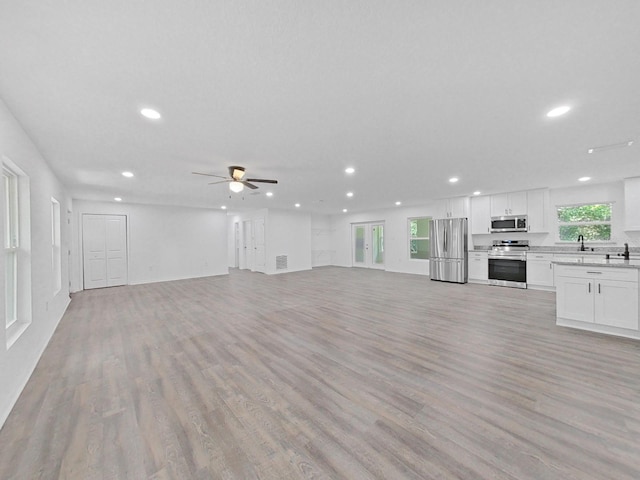 unfurnished living room featuring ceiling fan, sink, and light wood-type flooring