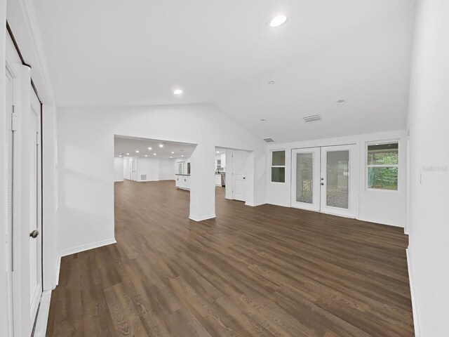 unfurnished living room featuring vaulted ceiling, dark hardwood / wood-style floors, and french doors