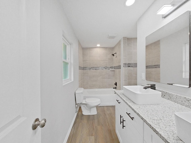 full bathroom with tiled shower / bath combo, vanity, wood-type flooring, and toilet