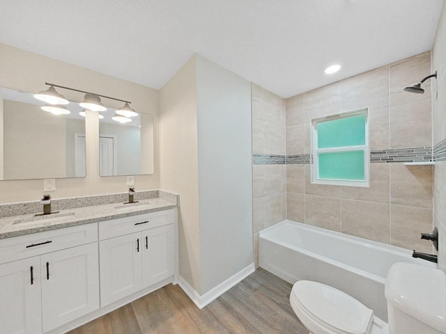 full bathroom featuring vanity, tiled shower / bath, wood-type flooring, and toilet