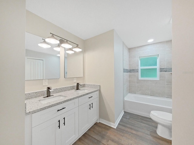 full bathroom with vanity, tiled shower / bath, hardwood / wood-style flooring, and toilet