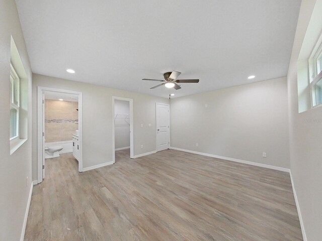 unfurnished bedroom with ceiling fan, connected bathroom, light hardwood / wood-style floors, a spacious closet, and a closet