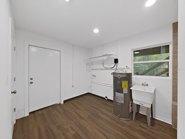 laundry area featuring dark wood-type flooring, sink, and water heater