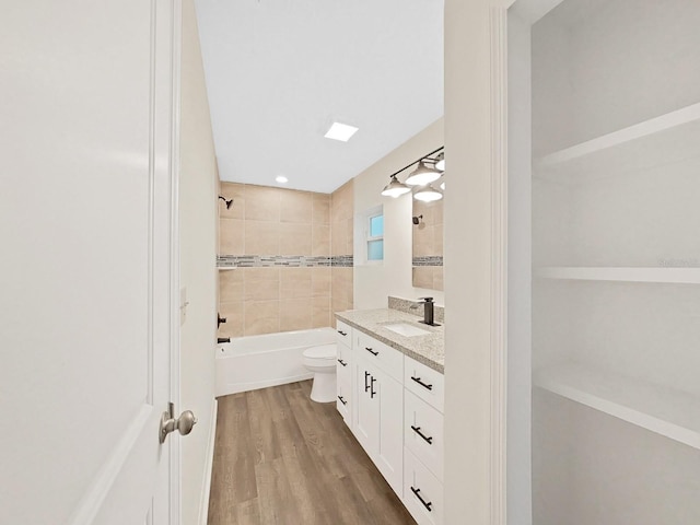 full bathroom with tiled shower / bath combo, wood-type flooring, vanity, and toilet