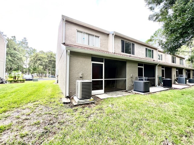 back of property with central air condition unit and a yard