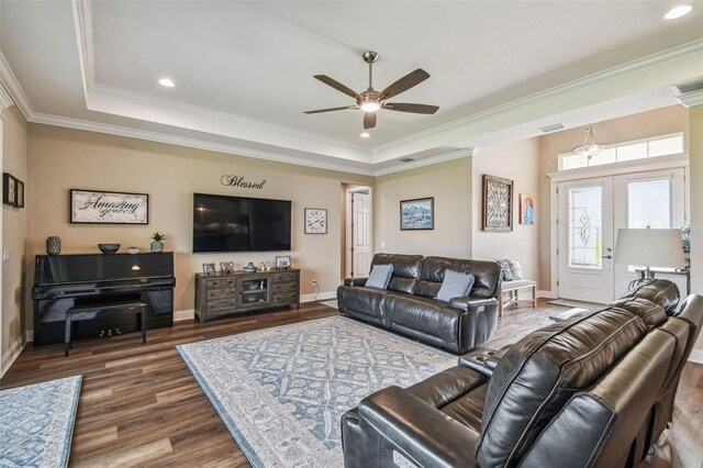 living room with ceiling fan, a raised ceiling, ornamental molding, and dark hardwood / wood-style flooring