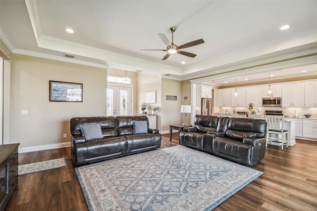 living room featuring ceiling fan, dark hardwood / wood-style floors, crown molding, and a raised ceiling