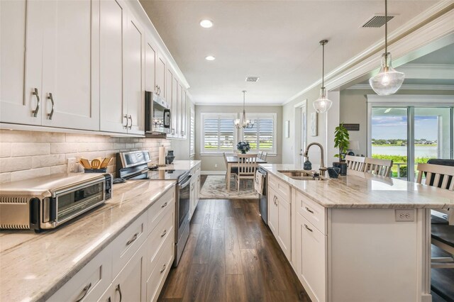 kitchen featuring dark wood-type flooring, tasteful backsplash, an island with sink, appliances with stainless steel finishes, and sink