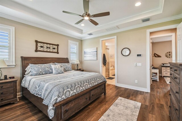 bedroom featuring dark hardwood / wood-style flooring, ensuite bath, a tray ceiling, and ceiling fan