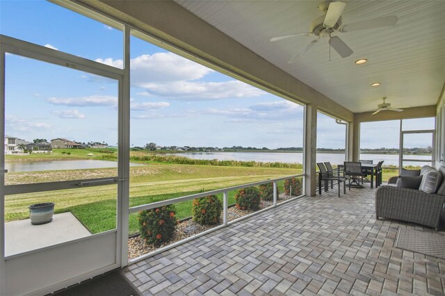 unfurnished sunroom with ceiling fan and a water view