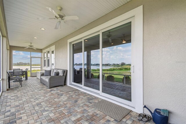 sunroom with ceiling fan and a water view