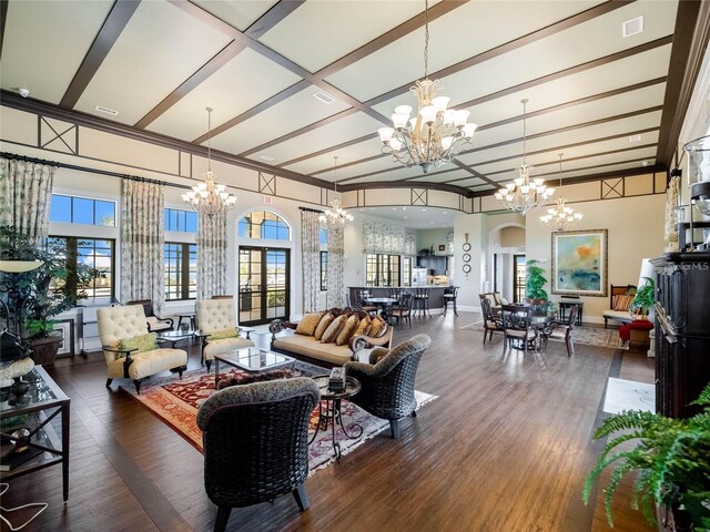 living room featuring dark hardwood / wood-style flooring, beam ceiling, an inviting chandelier, and a healthy amount of sunlight