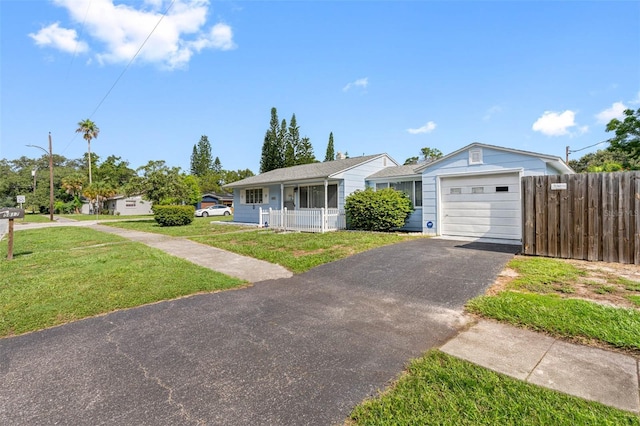 ranch-style house featuring a garage, aphalt driveway, covered porch, fence, and a front lawn