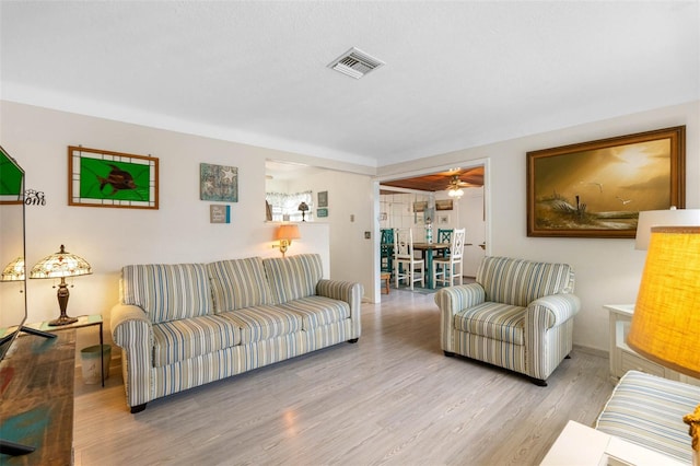 living room with wood finished floors, visible vents, and baseboards