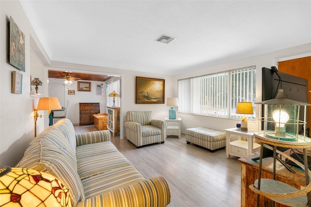 living room featuring wood finished floors, visible vents, and a ceiling fan