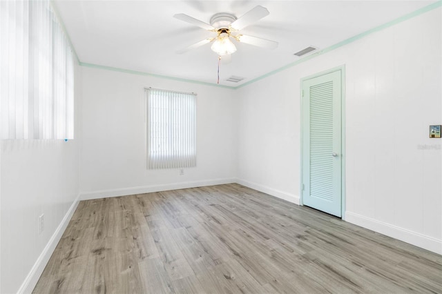 empty room with plenty of natural light, ceiling fan, visible vents, and wood finished floors