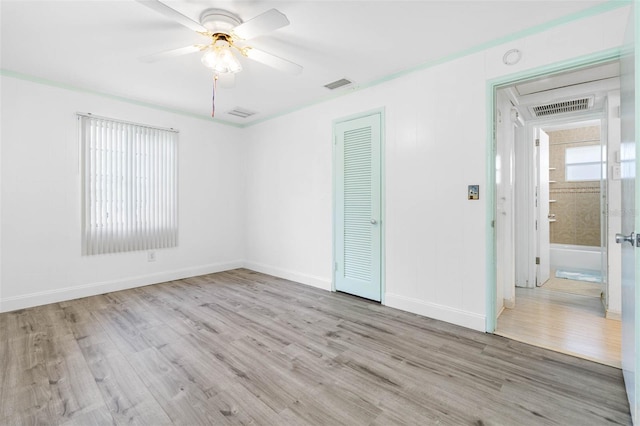 unfurnished room with baseboards, wood finished floors, visible vents, and a ceiling fan