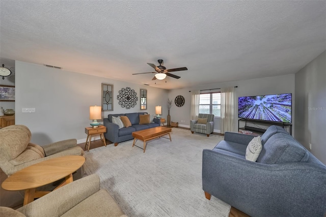 carpeted living room with ceiling fan and a textured ceiling