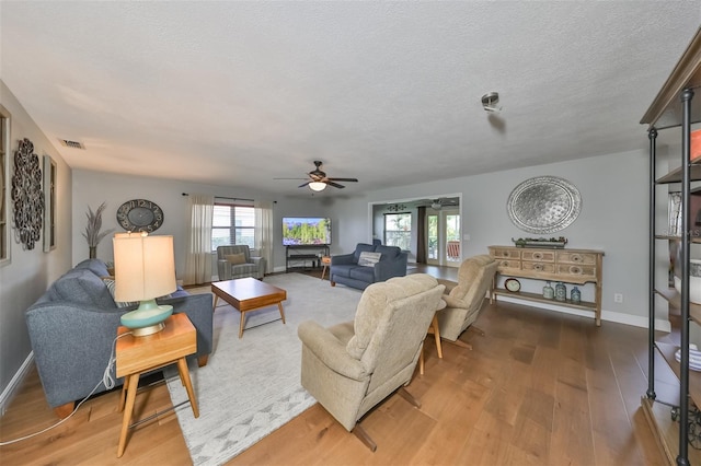 living room with ceiling fan, wood-type flooring, and a textured ceiling