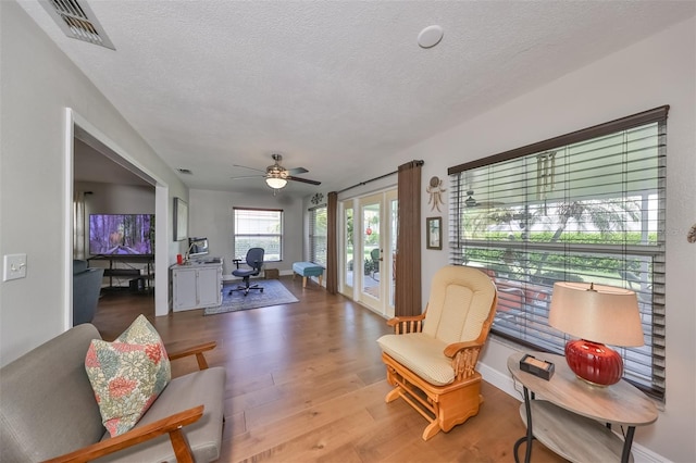 living room with ceiling fan, wood-type flooring, and a textured ceiling