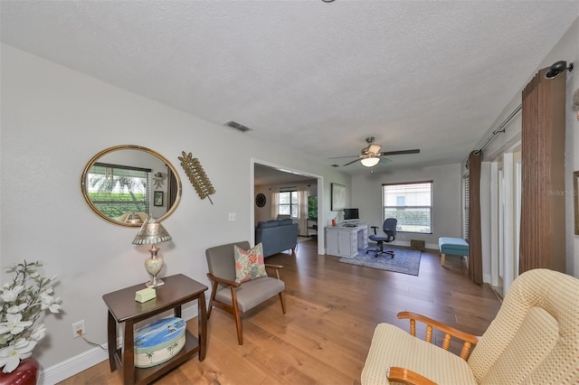 living room with ceiling fan, hardwood / wood-style flooring, and a textured ceiling