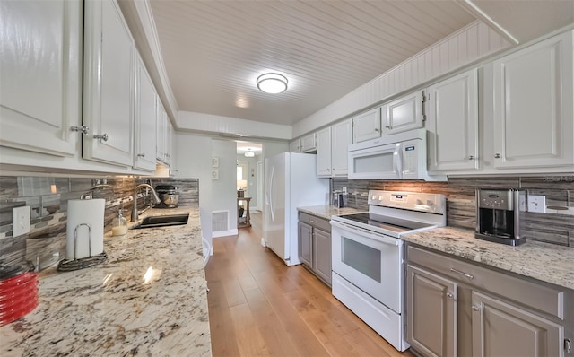 kitchen with backsplash, light wood-type flooring, white appliances, and sink