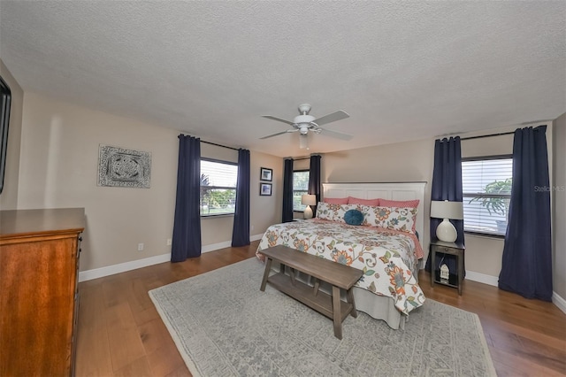 bedroom with ceiling fan, dark wood-type flooring, and a textured ceiling