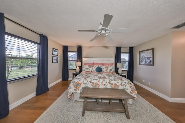 bedroom with ceiling fan, a textured ceiling, and hardwood / wood-style flooring