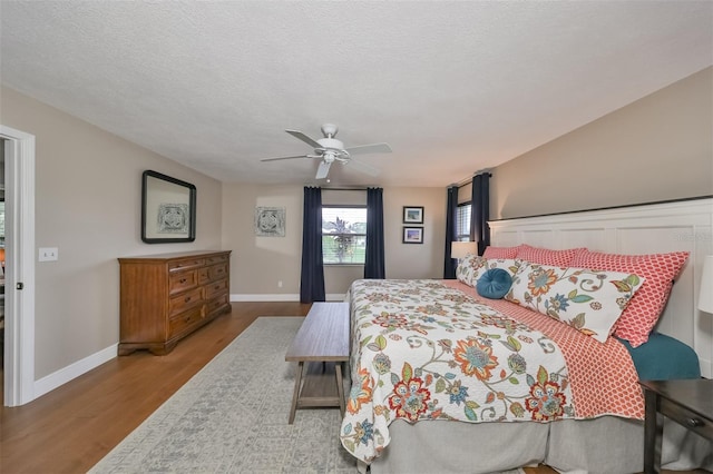 bedroom featuring ceiling fan, wood-type flooring, and a textured ceiling