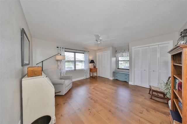 living area featuring ceiling fan, light hardwood / wood-style flooring, a textured ceiling, and plenty of natural light