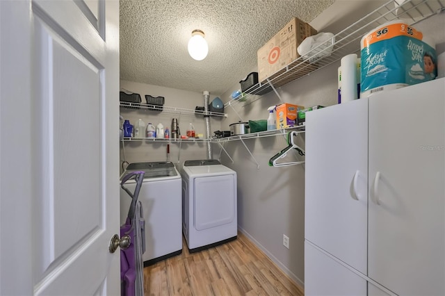 laundry room featuring light wood-type flooring, a textured ceiling, and washer and clothes dryer