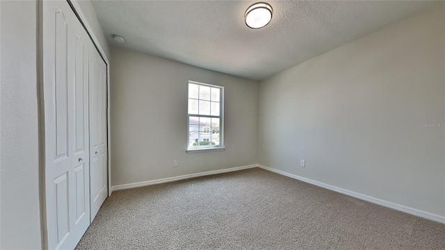 unfurnished bedroom with a textured ceiling, light carpet, and a closet