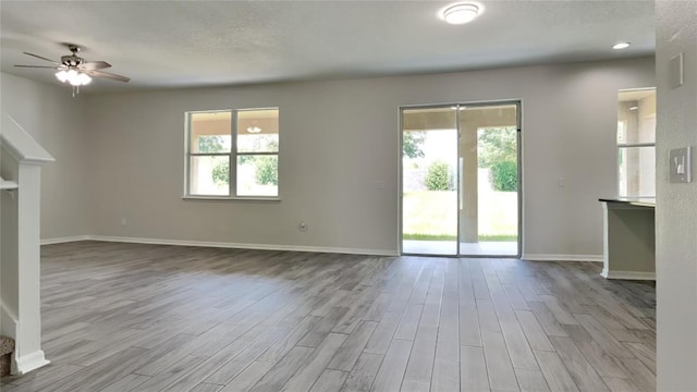 unfurnished living room featuring light hardwood / wood-style floors, ceiling fan, and a wealth of natural light