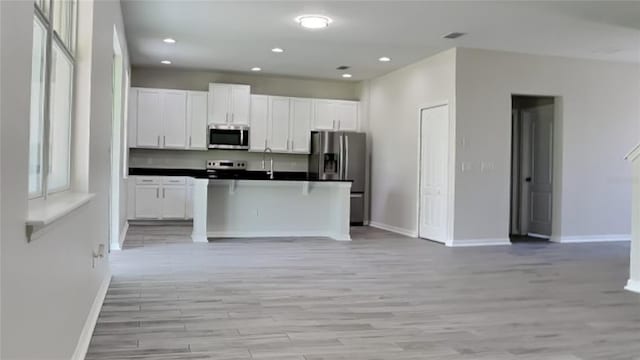 kitchen featuring light wood-type flooring, stainless steel appliances, and white cabinetry