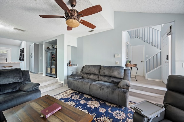 living room with visible vents, vaulted ceiling, stairway, and a textured ceiling